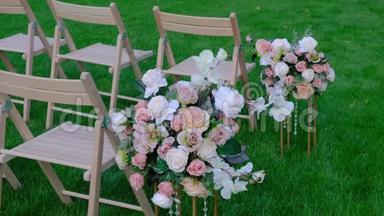 花束和绿色草地上的白色木制空椅子。 婚礼装饰。
